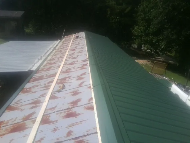 Old rusted panels beside newly installed green metal roofing — Wind Damage Roof Repair by Roofing Brothers in Hardeeville