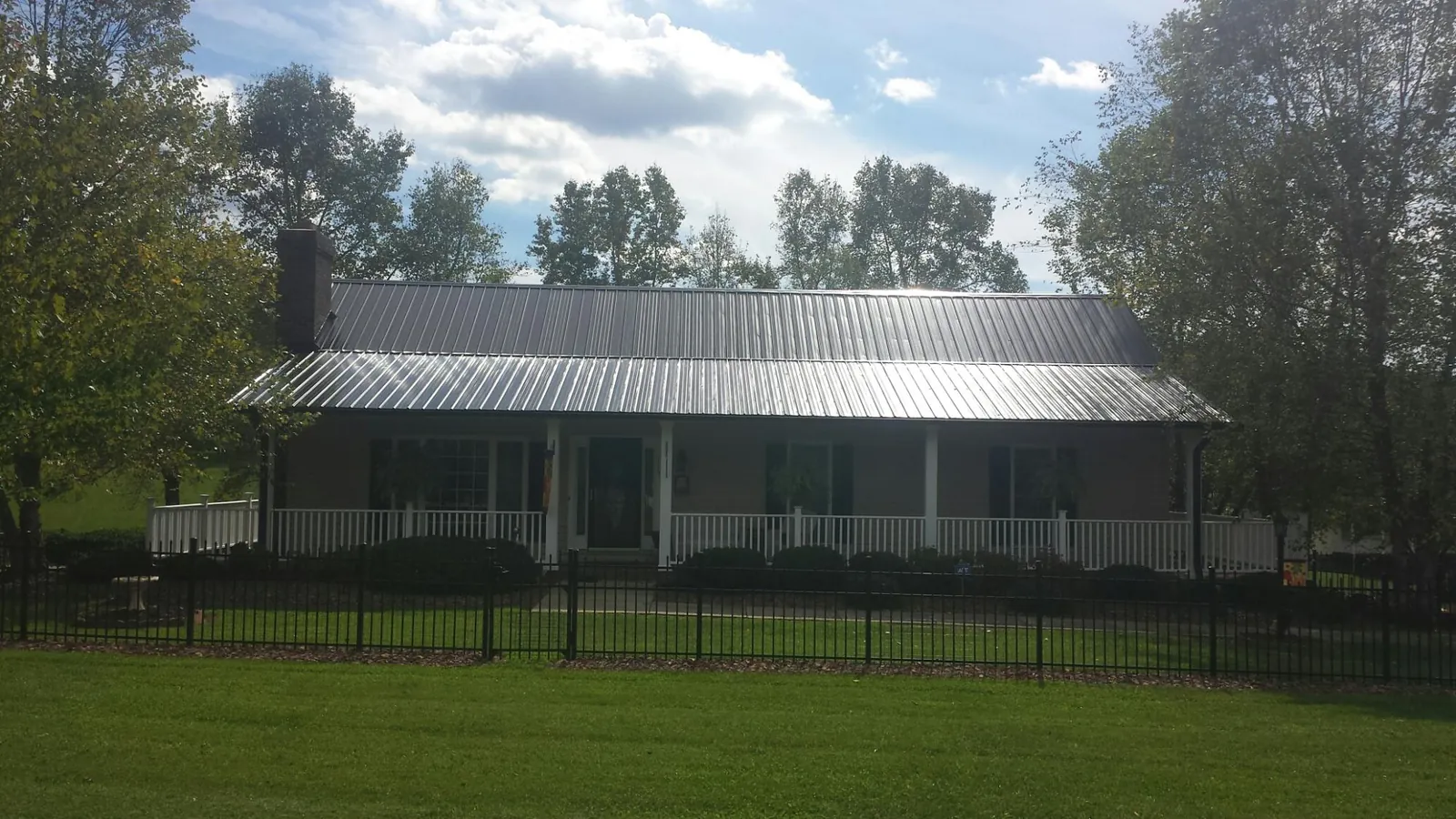 Gray metal roof on a brick ranch with a full width front porch — Gutter Guard Installation work by our crew in Hardeeville