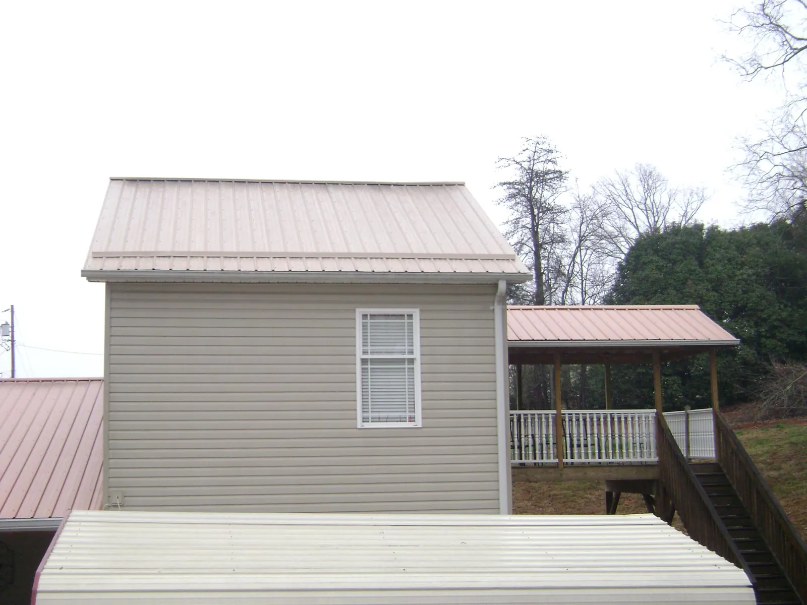 Tan metal roofs on a two story addition and attached porch, from a Roof Replacement job in Hardeeville